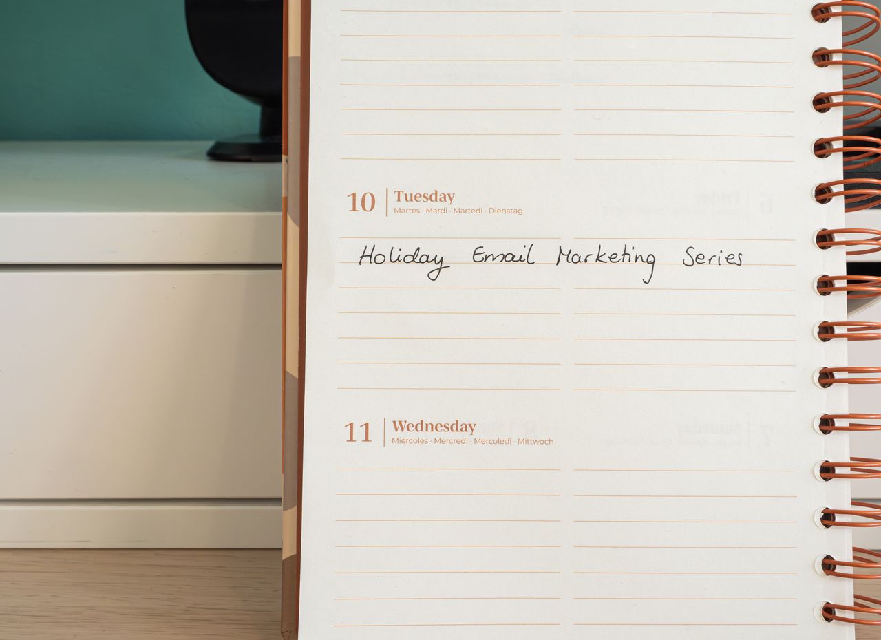 why-choose-us A planner lies open on a desk with a handwritten note that says Holiday Email Marketing Series.